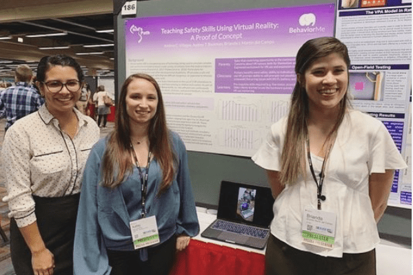 Three women presenting a scientific poster at a conference.
