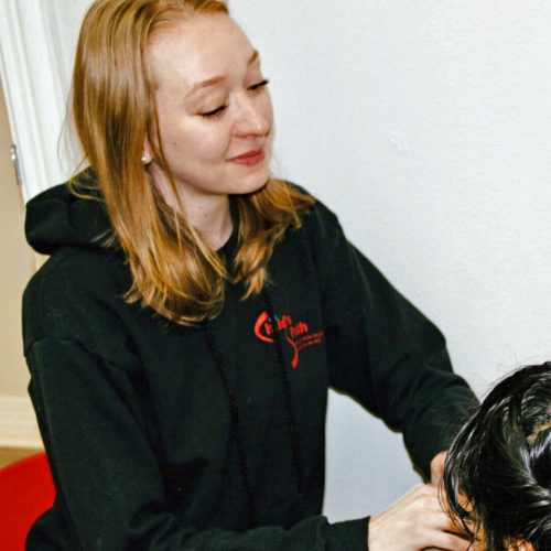 Woman with red hair wearing a black hoodie and smiling.