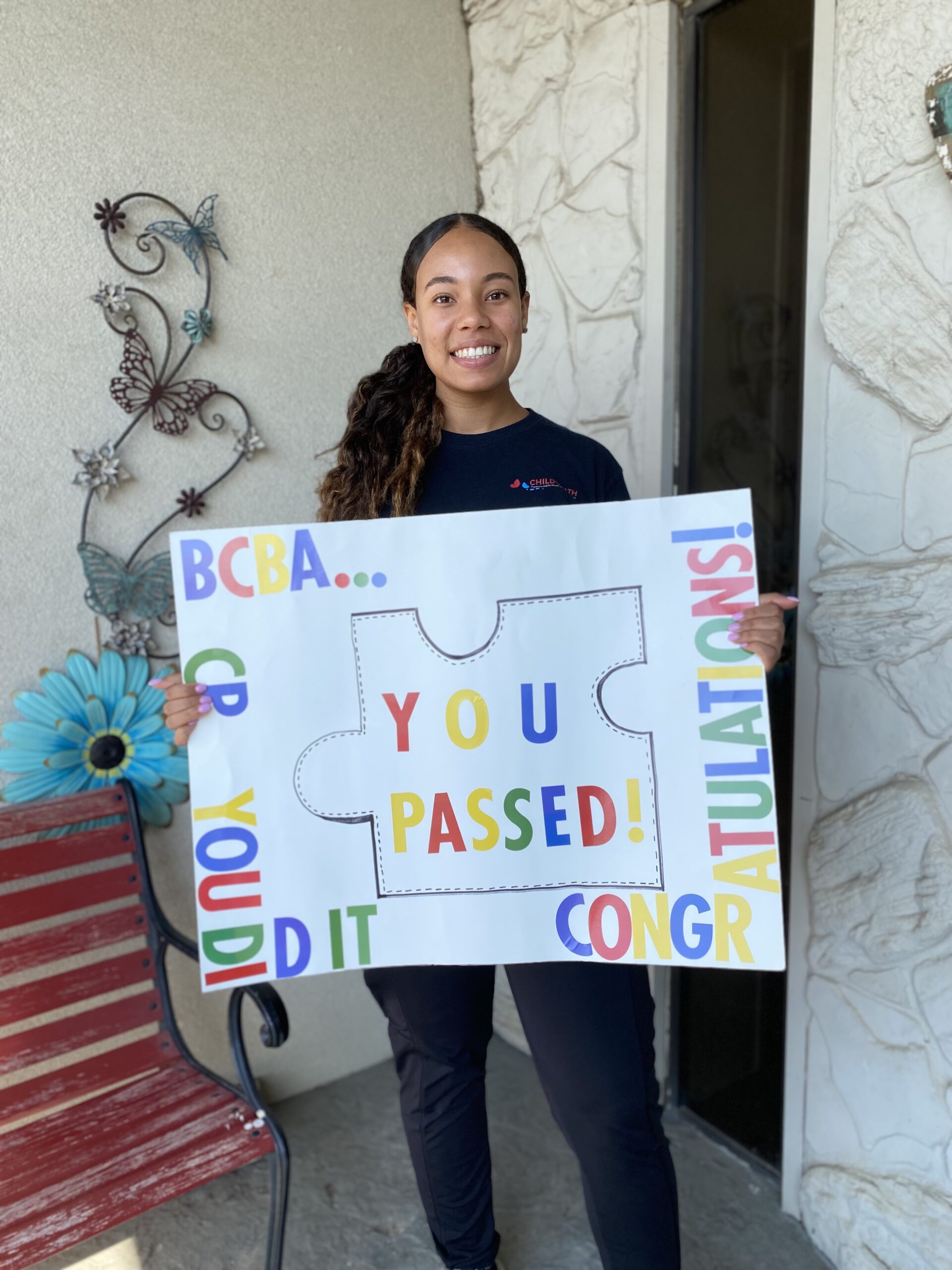A woman holding a colorful congratulatory sign that says 
