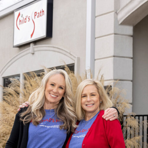 Two smiling women posing outside a building with a 'Cedar Point' sign.