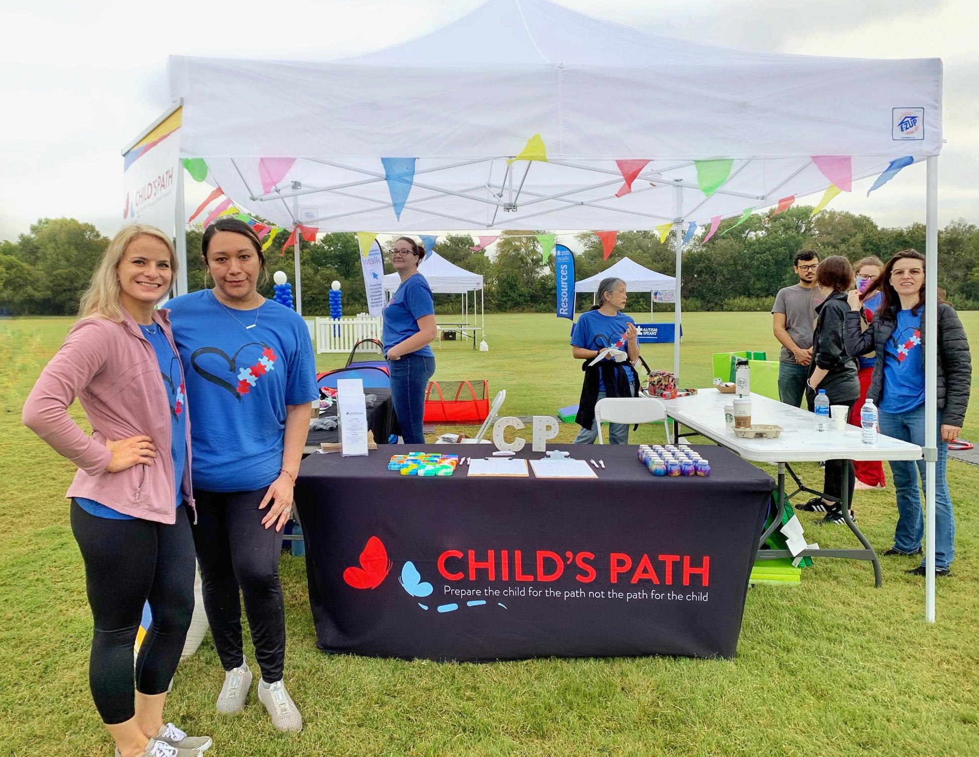 Volunteers at a Child's Path booth during an outdoor event.