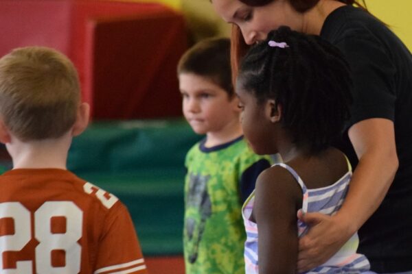 Teacher guiding children in a colorful classroom.