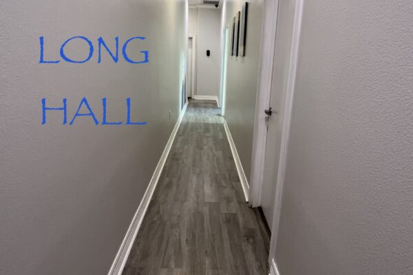 Long narrow hallway with gray walls and wooden flooring.