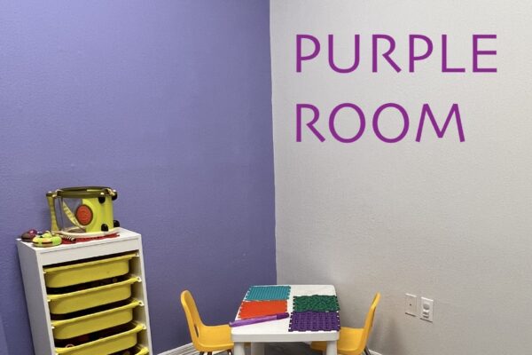 A small children's play area with a purple wall and white table.