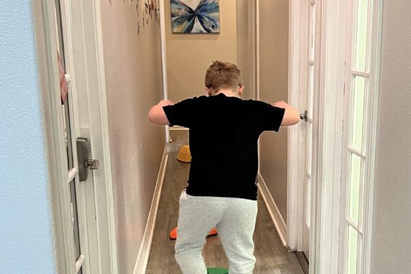 Child in colorful socks and yellow shoes posing in a narrow hallway.