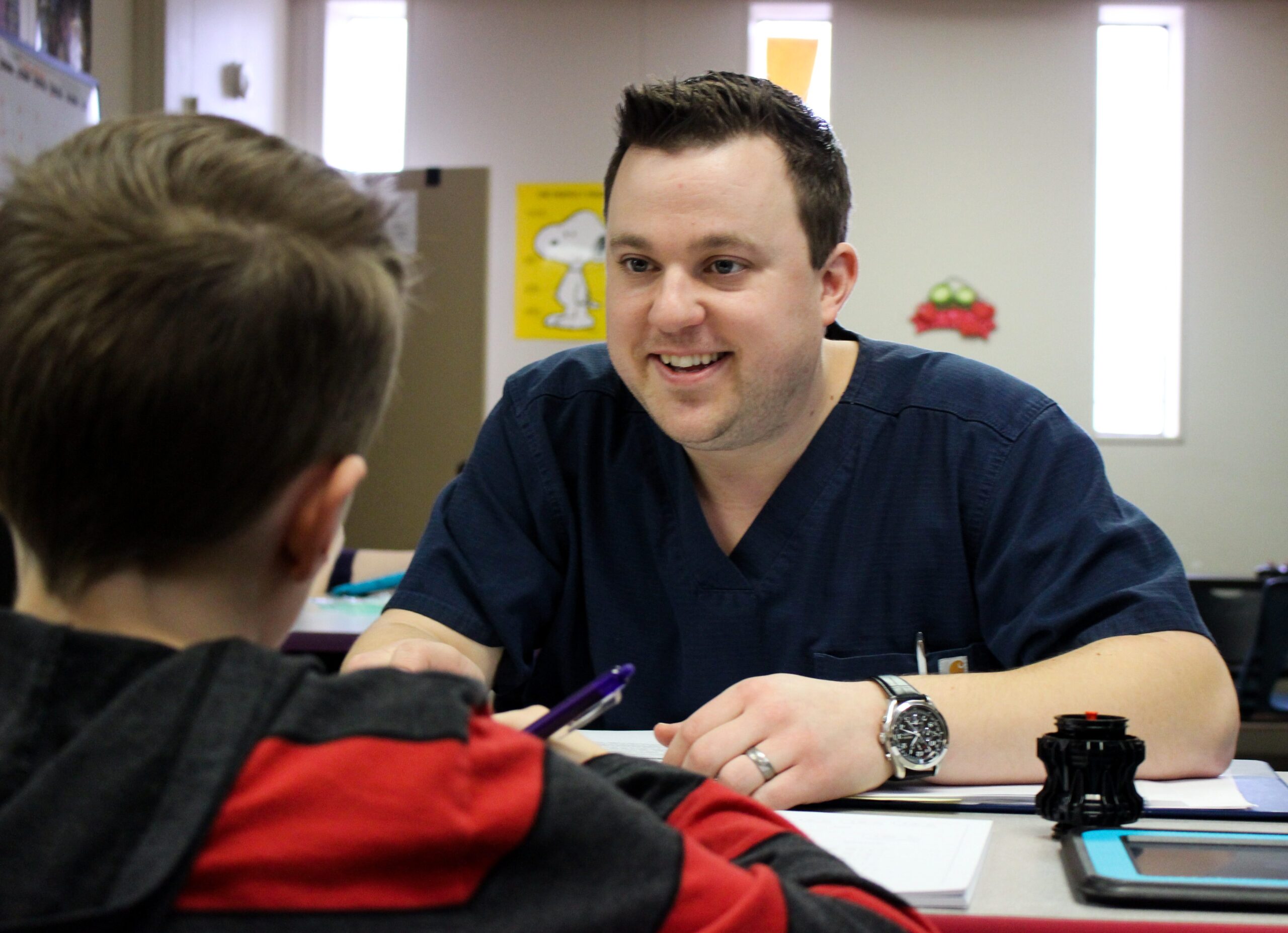 Teacher smiling and engaging with a student during a classroom session.