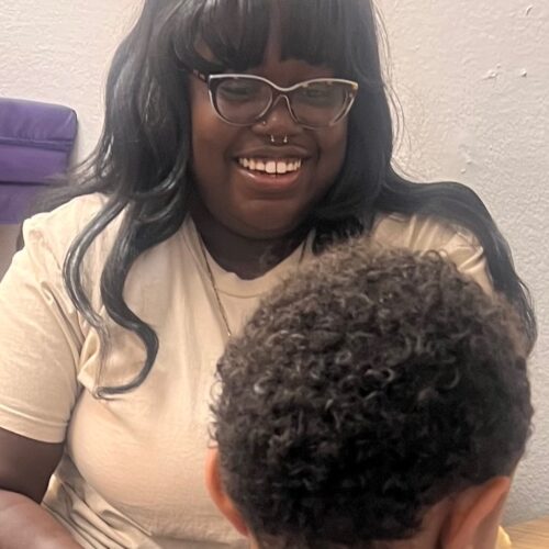 Smiling woman with glasses and a child with curly hair.