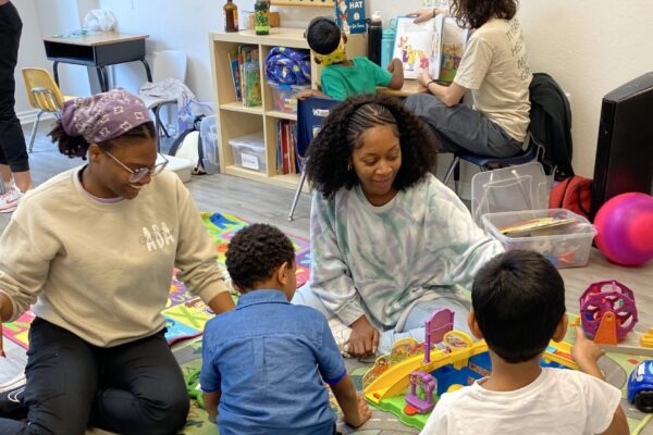 Children and adults playing with toys and reading in a cozy room.