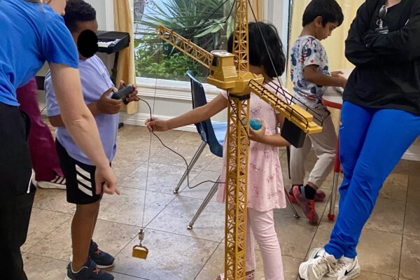 Children interacting with a traditional balance scale indoors.