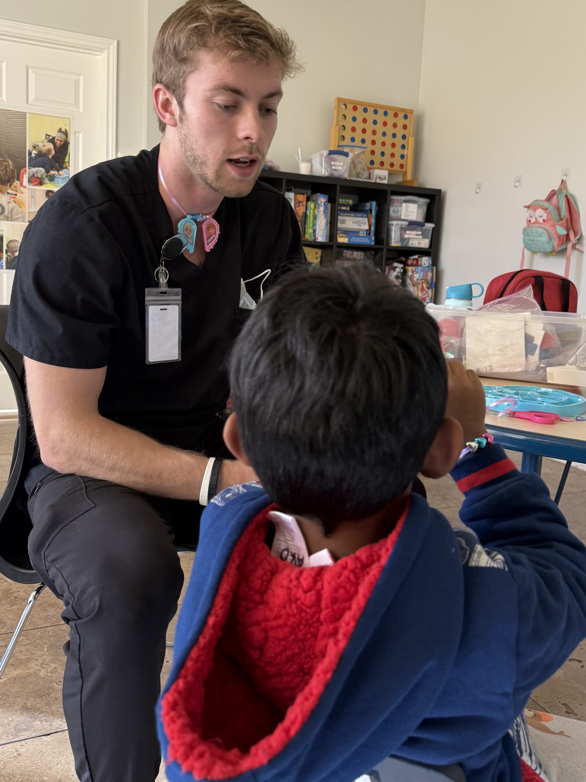 Man engaging with child in classroom setting.
